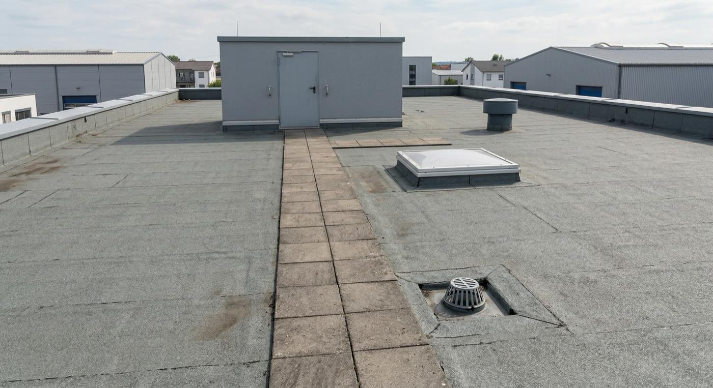 Flachdach eines Gewerbegebäudes im DACH-Raum mit Wartungsweg, Dachzugang und technischen Aufbauten