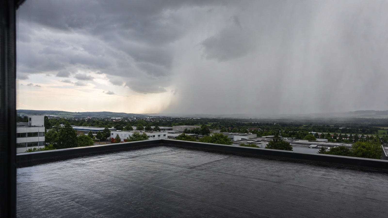 Heranziehende Regenwand über einem mitteleuropäischen Gewerbeflachdach
